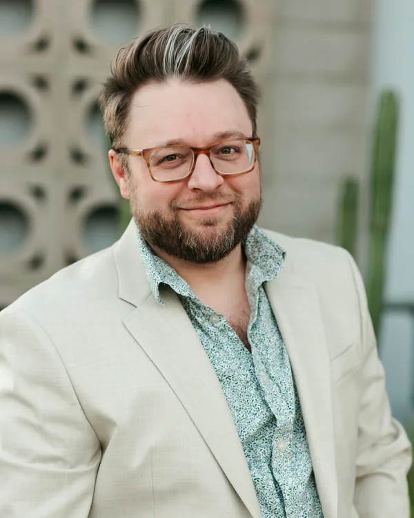 Jake Tlapek in a cream blazer with a calm half smile