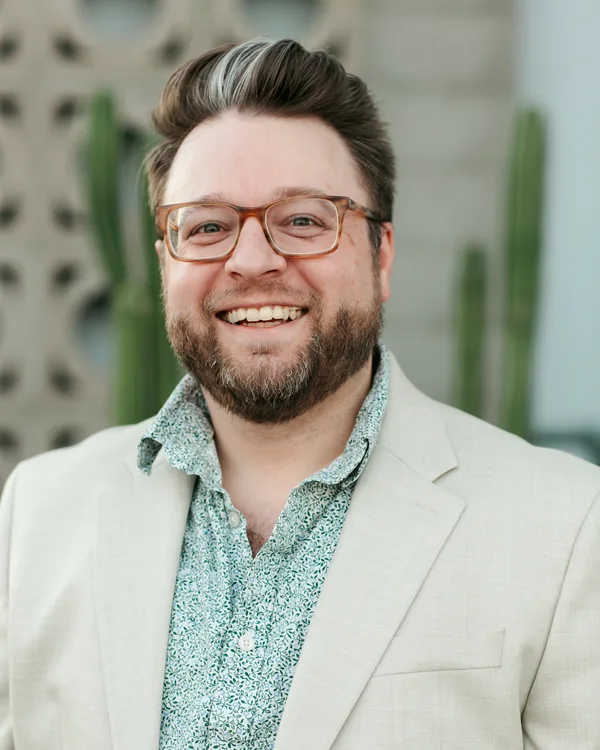 Jake Tlapek laughing in a cream blazer